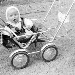 Baby in a stroller being pushed by a woman.