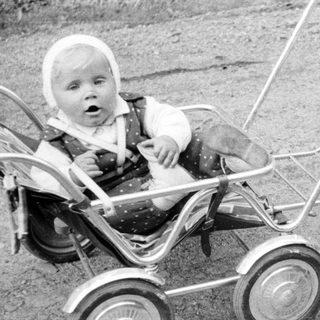 Baby in a stroller being pushed by a woman.