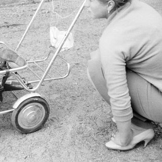 Baby in a stroller being pushed by a woman.