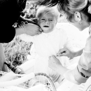 Woman tending to a crying baby in a stroller.