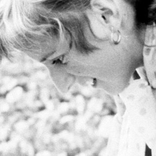 Here's a brief summary of the image: A person assists a young child into a white garment.