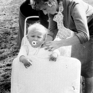 Woman tending to a baby in a vintage stroller.