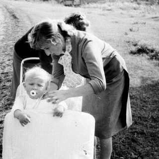 Woman tending to a baby in a vintage stroller.