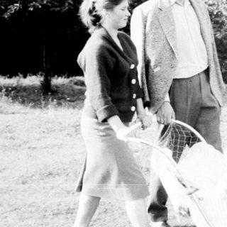 Couple walking with a baby carriage in a park.
