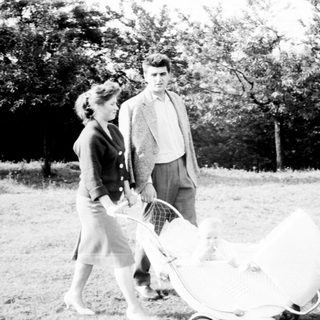 Couple walking with a baby carriage in a park.