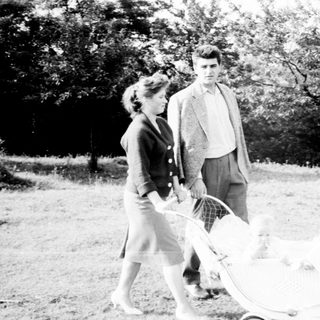 Couple walking with a baby carriage in a park.