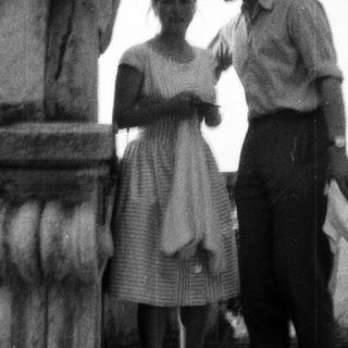 Couple standing near a column on a balcony.