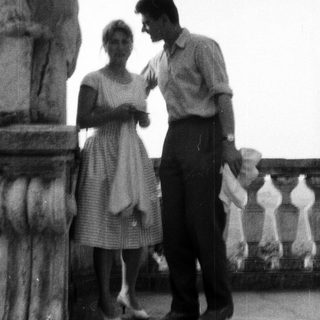 Couple standing near a column on a balcony.