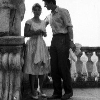 Couple standing near a column on a balcony.
