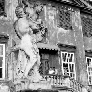 Statue and people on a balcony of an old building.