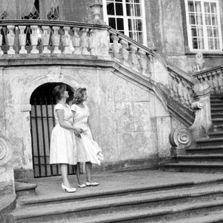 Two women stand on stone steps of an ornate building.