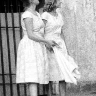 Two women stand on stone steps of an ornate building.