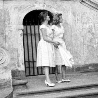 Two women stand on stone steps of an ornate building.