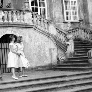 Two women stand on stone steps of an ornate building.