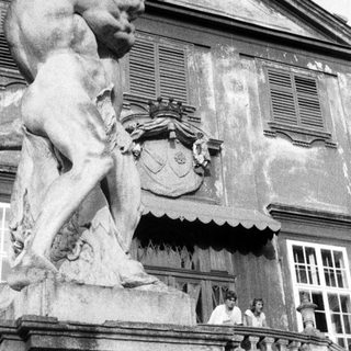 Statue of a man stands before an ornate building.