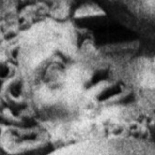 Statue of a man stands before an ornate building.