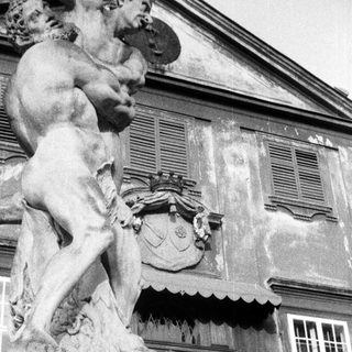 Statue of a man stands before an ornate building.