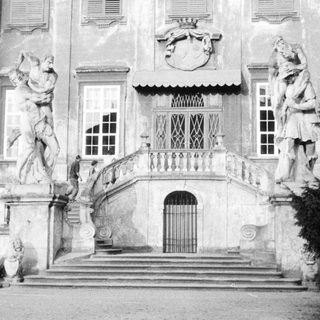 Monumental staircase with statues leading to a grand building.