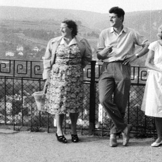 Three people pose outdoors, overlooking a landscape.