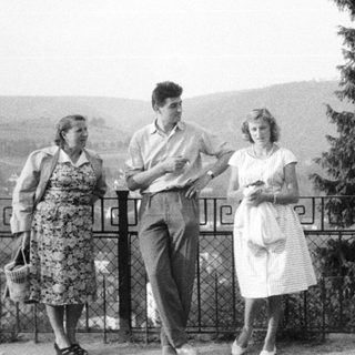 Three people standing outdoors, possibly overlooking a landscape.