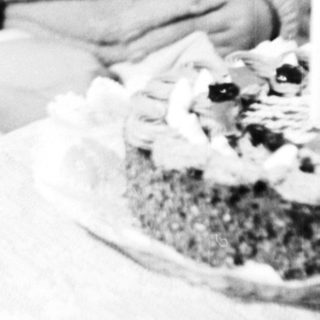 Woman holding child, seated near a cake.