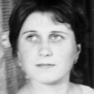 Woman holding child, seated near a cake.