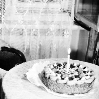 Here's a brief summary of the image: Child sits near a cake with a single candle.