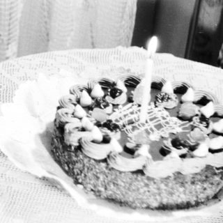 Baby sits in chair next to a birthday cake.