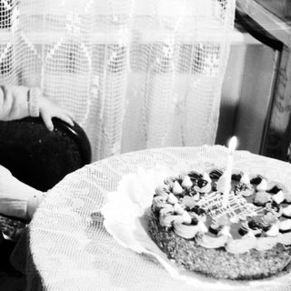 Baby sits in chair next to a birthday cake.
