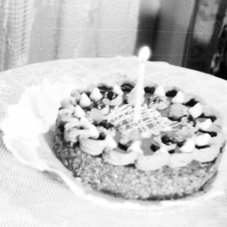 Child sits near a cake with a single candle.
