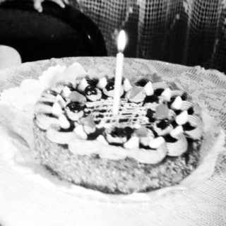 Baby sits near a cake with a single candle.