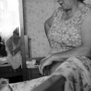 Woman and girl in a bedroom, reflected in a mirror.