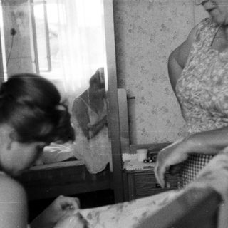 Woman and girl in a bedroom, reflected in a mirror.