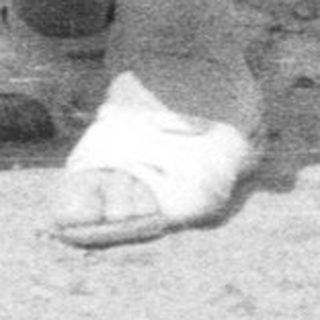 Baby takes first steps near a farmhouse, woman watching.