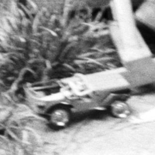 Boy riding a rocking horse outdoors, vintage black and white photo.