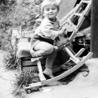 Boy riding a rocking horse outdoors, vintage black and white photo.