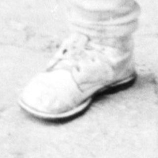 Black and white photo of a young boy standing outside.