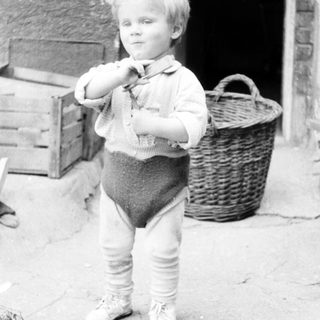 Black and white photo of a young boy standing outside.