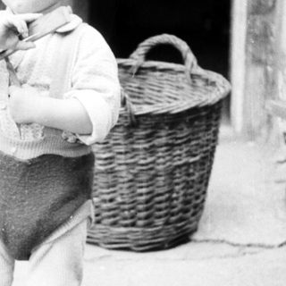 Black and white photo of a young boy standing outside.