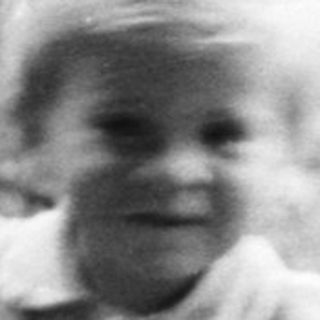Child stands near a basket, woman sits nearby.