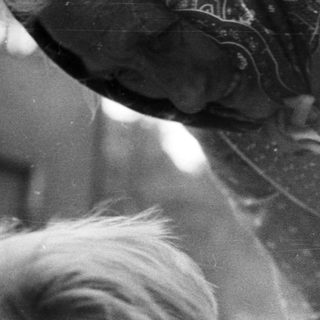 Here's a brief summary of the image: Black and white image of a child and an adult's hands.