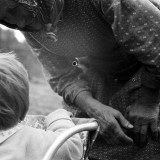 Here's a brief summary of the image: Black and white image of a child and an adult's hands.