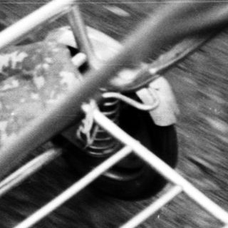 Here's a brief summary of the image: Baby sits in a vintage stroller outdoors.