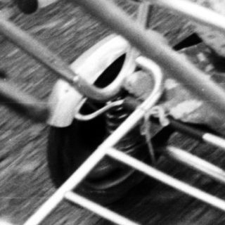 Baby seated in a vintage wheeled stroller outdoors.
