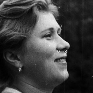 Here's a brief summary of the image: Woman in profile, smiling, looking off into the distance.