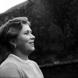 Here's a brief summary of the image: Woman in profile, smiling, looking off into the distance.
