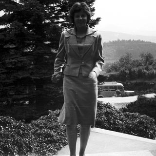 Woman in a suit stands outdoors on stone steps.