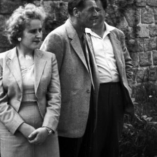 Couple standing near a stone wall in a black and white photo.