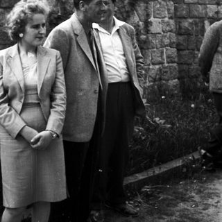 Couple standing near a stone wall in a black and white photo.
