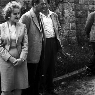 Couple standing near a stone wall in a black and white photo.